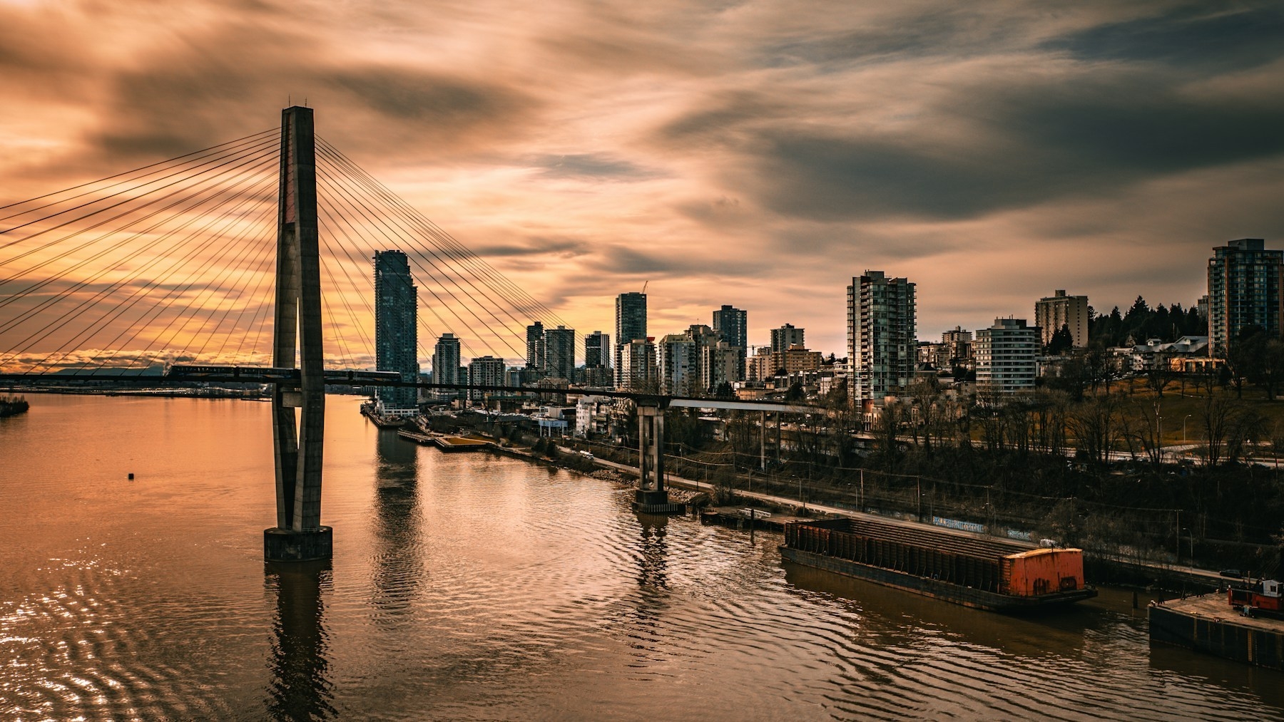 New Westminster&rsquo;s riverfront skyline and cable-stayed bridge over the Fraser River at sunset